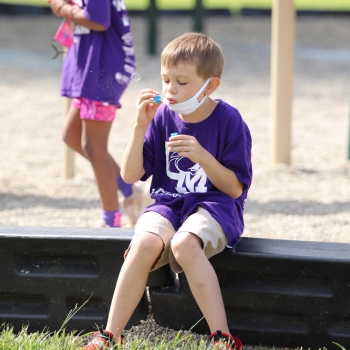 student outdoors sitting and blowing bubbles